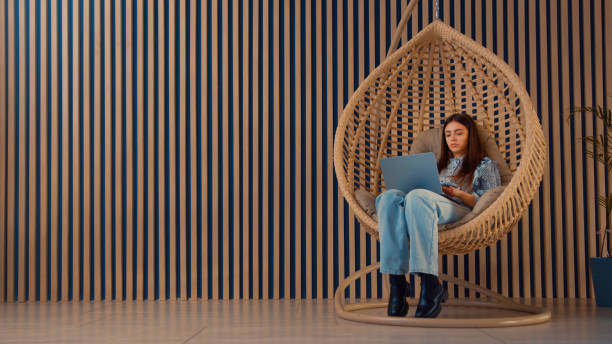 istock Young woman is working while sitting in a cozy hanging  swing chair 1476124143