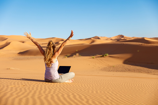 Freelancer woman work on computer in the sahara desert- work,  freelance,  booking or travel concept