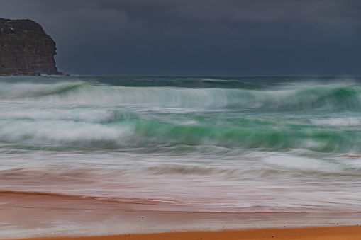 Sunrise with rain clouds and good sized waves at  Macmasters Beach on the Central Coast, NSW, Australia.