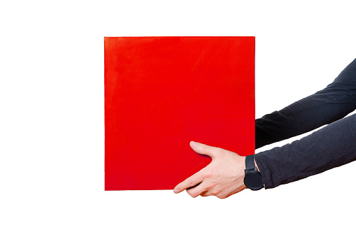 Pair of hands wearing a black long-sleeved shirt hold a large red box isolated on white. Bold and modern delivery services, e-commerce and logistics related background with copy space.