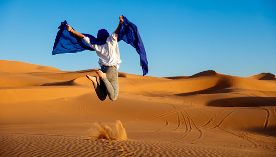 Woman tourist jumping in the Sahara desert