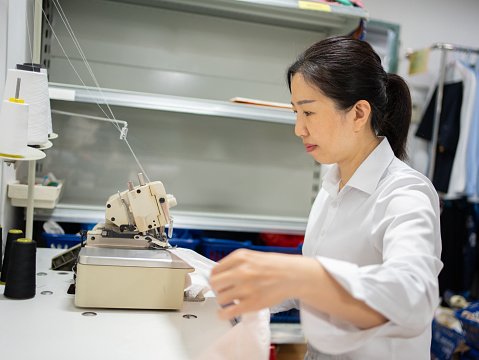 Asian female worker using a seaming machine
