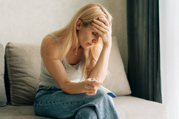 istock Upset sad woman holding pregnancy test while sitting on sofa at home. 1476136590
