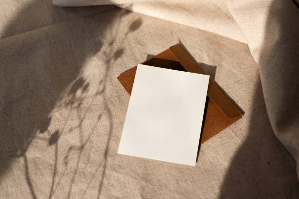 istock Blank paper card, envelope on neutral beige background, harsh sunlight floral shadows on sunset. Aesthetic summer, autumn business branding template, copy space 1476138997
