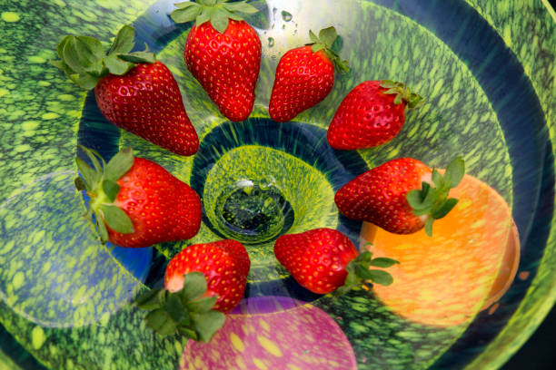 red strawberries in multicolored bowl background