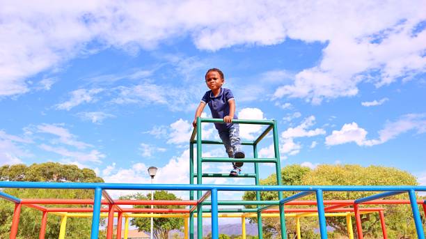 Young black African boy playing on monkey bars in a park