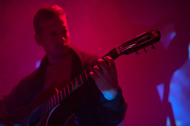 musician playing acoustic guitar in a foggy club with colorful lights. - fingerstyle imagens e fotografias de stock