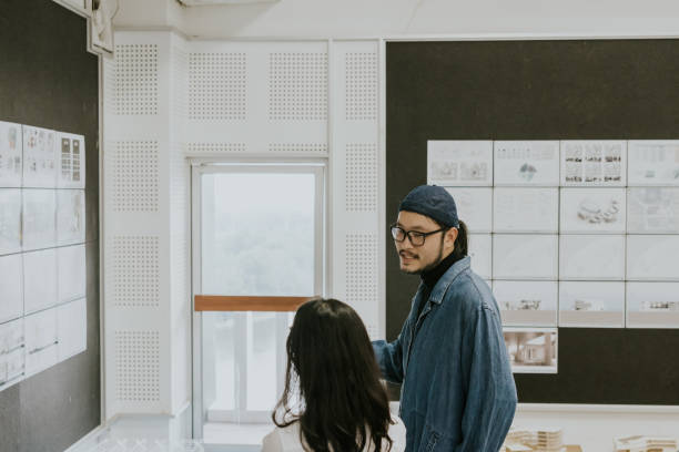 istock Asian architects partner talking about fictional design of student's work at the auditorium 1476148264
