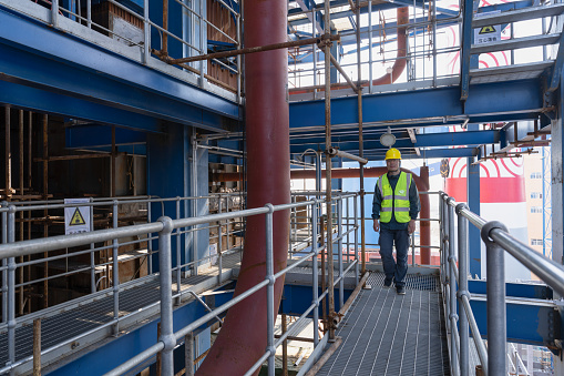 A male worker walks on the stairs of a chemical plant