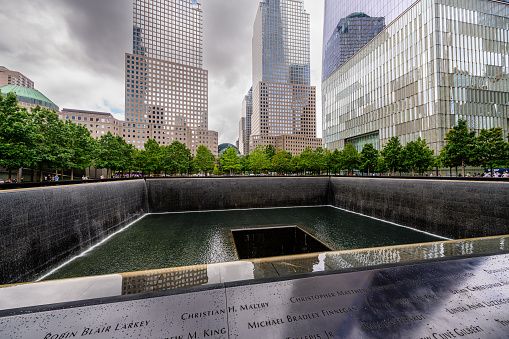 June 18, 2022: Wide angle view of the Ground Zero 9/11 Memorial in Lower Manhattan, New York City, USA. New York architecture in the background.