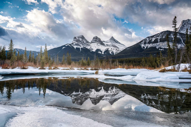 istock Three Sisters Mountains with snow covered on frozen bow river reflection in the morning on winter 1476153686