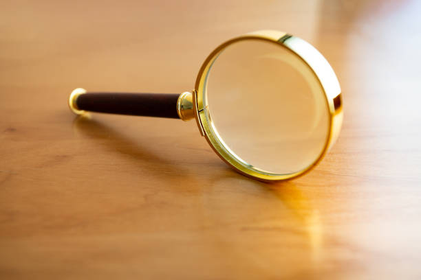 Golden magnifying glass on brown desk