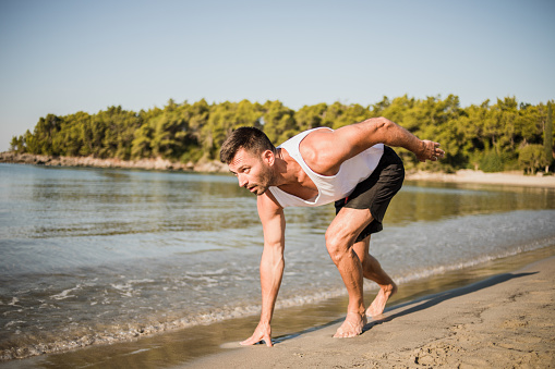 A young man exercises in the morning by the sea, the concept of a healthy lifestyle, iodine vapor from the sea has a good effect on the respiratory tract, and exercising by the sea is very pleasant to the body