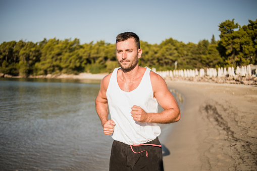 A young man exercises in the morning by the sea, the concept of a healthy lifestyle, iodine vapor from the sea has a good effect on the respiratory tract, and exercising by the sea is very pleasant to the body