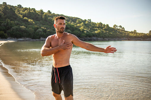 A young man exercises in the morning by the sea, the concept of a healthy lifestyle, iodine vapor from the sea has a good effect on the respiratory tract, and exercising by the sea is very pleasant to the body