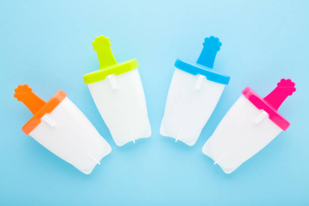 istock White plastic containers for homemade ice popsicle on colorful sticks. Light blue table background. Pastel color. Closeup. Cold sweet snack in summer. Top down view. 1476160387