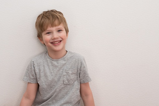 Portrait of happy adorable european boy in casual outfit over white background.Cute blond hair boy in grey T-shirt. High quality photo