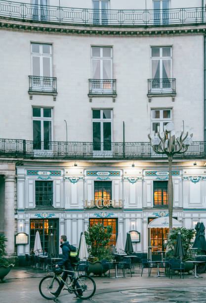 March 8th 2023, Nantes Brittany France: Locals walking on the street on a rainy day in Nantes, which is one of the most popular cities to tourists in France. La Cigale restaurant can be seen in the image.