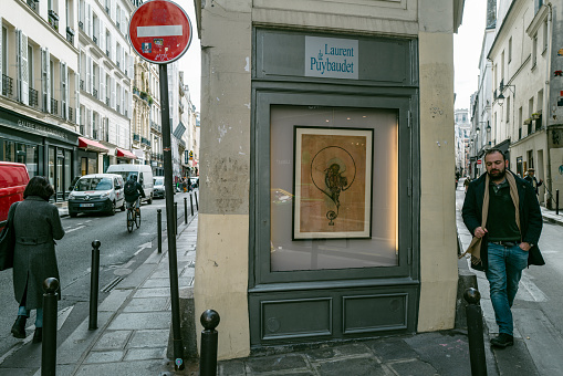 Paris,France,March 7th 2023: A man walking past a small gallery at Saint-Germain area in Paris.Saint-Germain area is famous to tourists for its chic and abundance of cafes, restaurants and galleries.