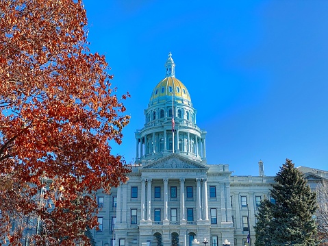 The Colorado State Capitol Building as photographed on an autumn day is , located at 200 East Colfax Avenue in Denver, Colorado, United States, is the home of the Colorado General Assembly and the offices of the Governor of Colorado and Lieutenant Governor of Colorado.\n\nThe building is intentionally reminiscent of the United States Capitol. Designed by Elijah E. Myers, it was constructed in the 1890s from Colorado white granite, and opened for use in November 1894. The distinctive gold dome consists of real gold leaf, first added in 1908, commemorating the Colorado Gold Rush. The building is part of Denver's Civic Center area. It was listed on the National Register of Historic Places as part of the Civic Center Historic District in 1974 and became part of the Denver Civic Center National Historic Landmark District in 2012.