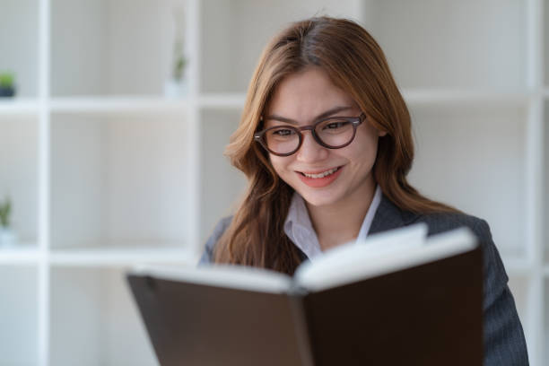 istock Close-up pretty young woman with glasses reading a book. 1476164811