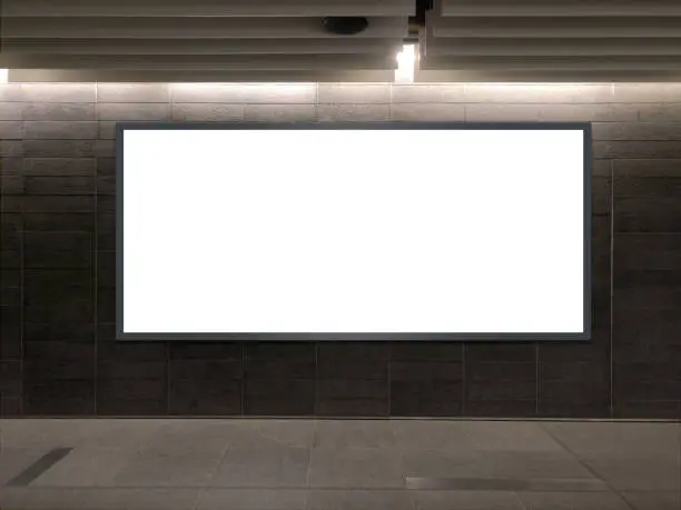 Photo of Horizontal blank advertising banners posters mockup in underground tunnel walkway; out-of-home OOH media display space, lightbox; 12 sheet template