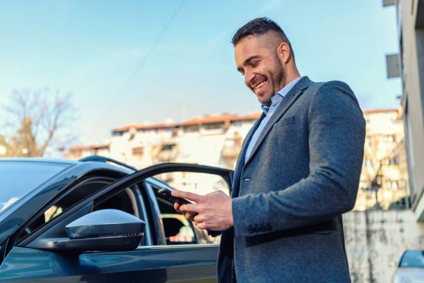 istock Businessman standing near his car and using smartphone 1476167807