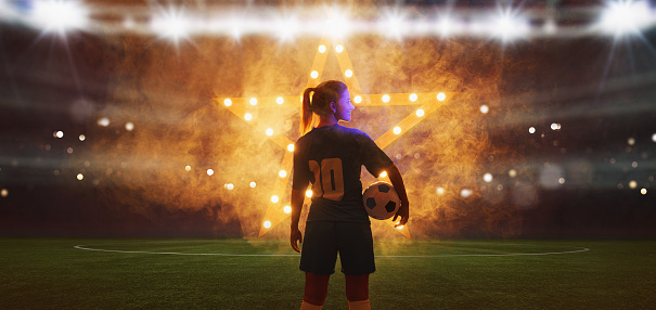 Portrait of young female soccer player with soccer ball standing with a shining star in the back