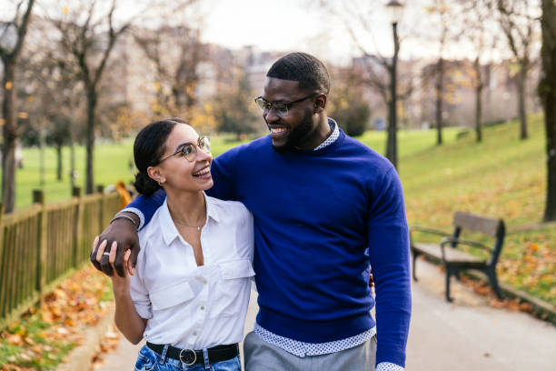 Joyful Interracial Couple Embracing in Autumn Park at Sunset - Handsome Black Boy and Pretty Caucasian Girl in Casual Outfits