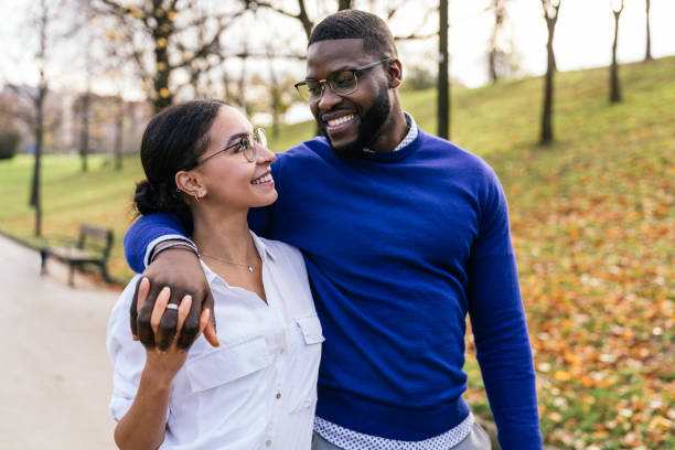 Interracial Couple Embracing in Autumn Park: Handsome Black Boy and Beautiful Caucasian Girl Walking and Smiling Happily at Sunset