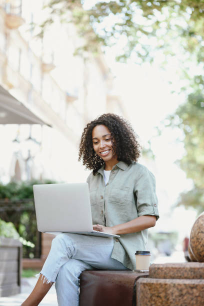 Happy woman using laptop in a city stock photo