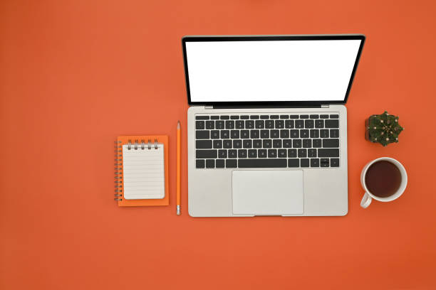 istock Top view of Office desk, Copy space and Creative space with empty screen of laptop, coffee cup, note paper on orange background. 1476181891