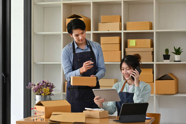 istock Small Start-up and SME owner, an Asian female entrepreneur using mobile phone, checking orders to organize products before sending to customers and working with employee male. 1476183782