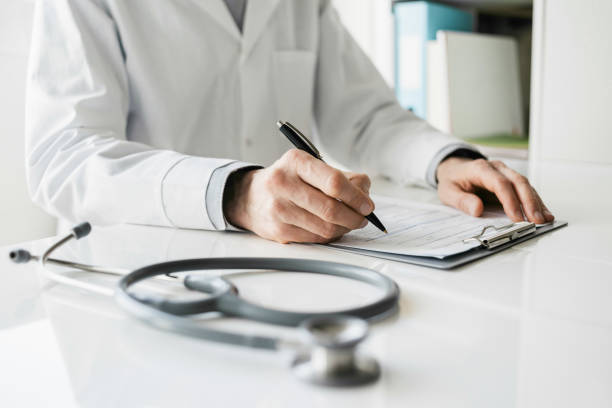 Doctor medical professional taking notes writing a prescription for patient stock photo
