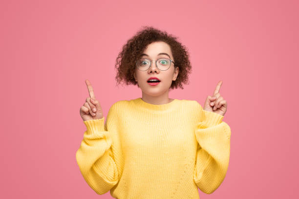 istock Amazed woman pointing up in studio 1476194955