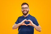 Cheerful bearded man showing heart gesture