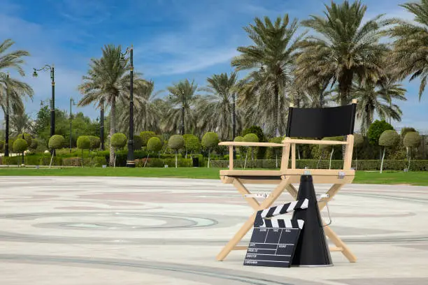 Photo of Director Chair, Movie Clapper and Megaphone on an Empty City Street with Palm Trees. 3d Rendering