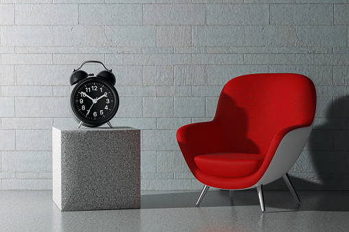 Alarm Clock with Empty Red Modern Oval Shape Relax Chair in front of stone blocks wall background. 3d Rendering