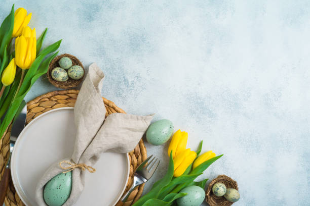 istock Easter festive table setting with easter eggs, plate and yellow tulips flowers on modern background. Top view, flat lay 1476200796