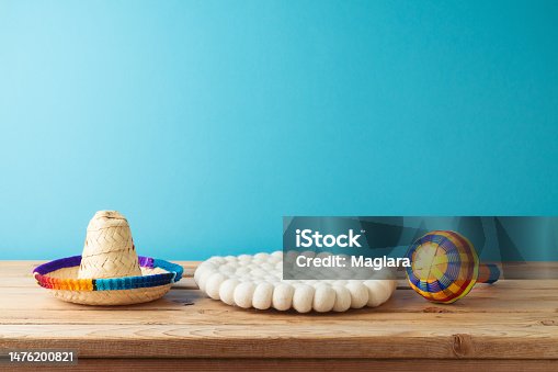 istock Table with empty space, maracas and sombrero hat  over blue background. Mexican party mock up for design and product display 1476200821