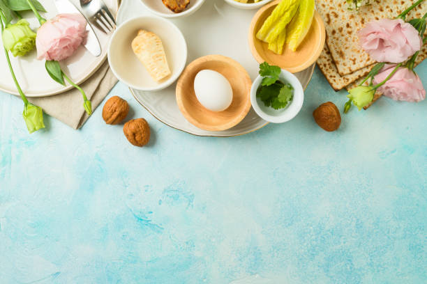 istock Jewish holiday Passover festive table setting with matzah, seder plate and spring flowers on blue  background. Top view, flat lay 1476200832