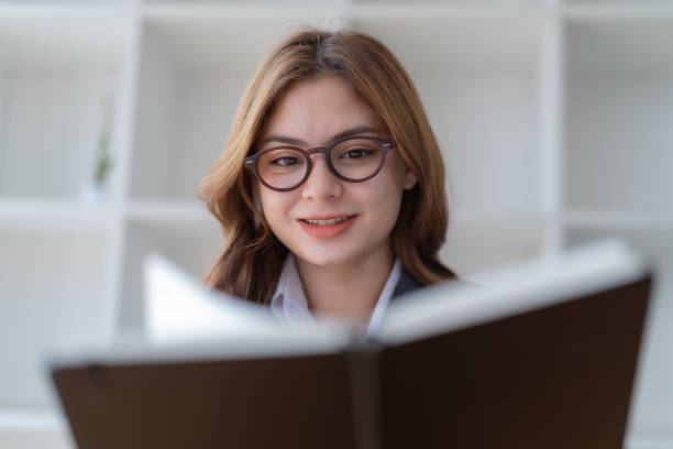 istock Close-up pretty young woman with glasses reading a book. 1476201350