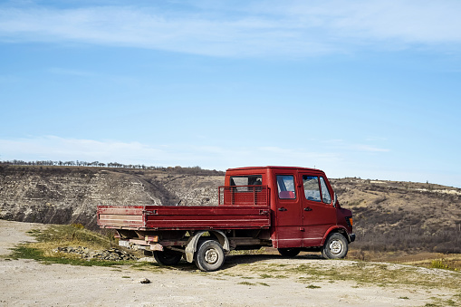 Old Orhei, Moldova - November 6, 2019: The old little red truck stop at the edge of the cliff. Scenic Mountain View. Blue sky.