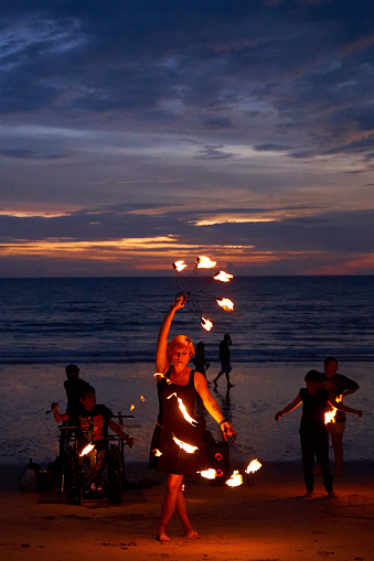 street performers put on a fire show for tourists on the beach after sunset. Thailand, Krabi - 10.12.2022