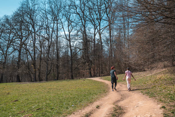 Indian female and Asian male running in a public park. Joggin together on a lovely sunny day wearing sports clothing.