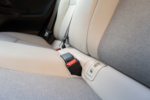 Shallow focus of the Isofix child safety attachment system seen on the rear seats of a new technology, hybrid car. Buckles for the rear passengers can be seen.