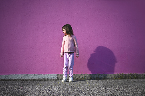 cute little girl standing outdoors on a sidewalk.