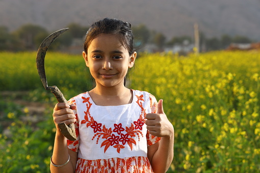 Indian farmer girl holding the sickle in hand and portraying a happy Indian agriculture concept.