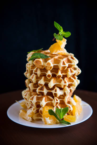 istock Cooked sweet Belgian waffles with oranges on a black 1476205895