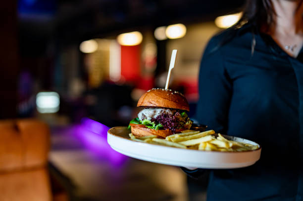 kellnerin hält teller mit burger und pommes frites im café - sandwich plate food french fries stock-fotos und bilder